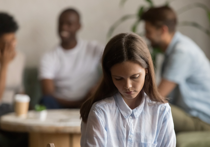 An adolescent girl looks down and appears sad, while peers talk in the background. CBT helps children and parents learn to cope with anxiety. 