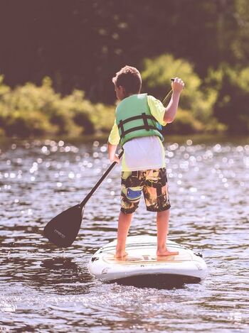 Child standing on paddle board. Facing fears is an important part of CBT treatment.