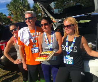Four psychologists standing in front of car on a sunny day in South Florida. Dr. Penela holds desserts in celebration of her birthday.