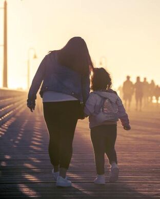 Mom and child walking at sunset. Enjoying outdoors is helpful to calm the mind and relieve anxiety. Learn more about Space Therapy today.
