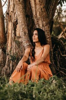 Mujer sentada frente de un árbol. Pasar tiempo afuera puede aliviar síntomas de ansiedad y del TOC.