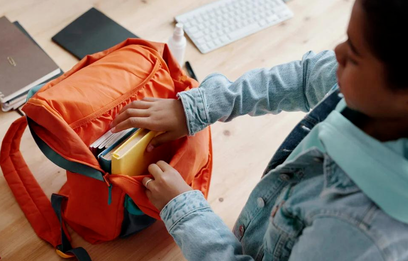 Child prepares their backpack for school the next day. It's normal to feel anxiety about returning to school, but parents can help children use effective coping tools.